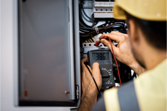 A technician tests the electrical system for a business premises ensuring that there are no faults
