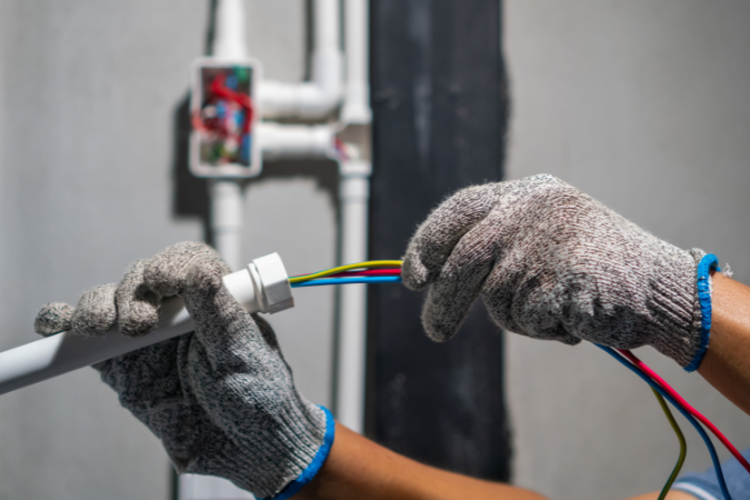 An electrician fitting wires into a PVC casing to show how to choose the right electrical contractor.